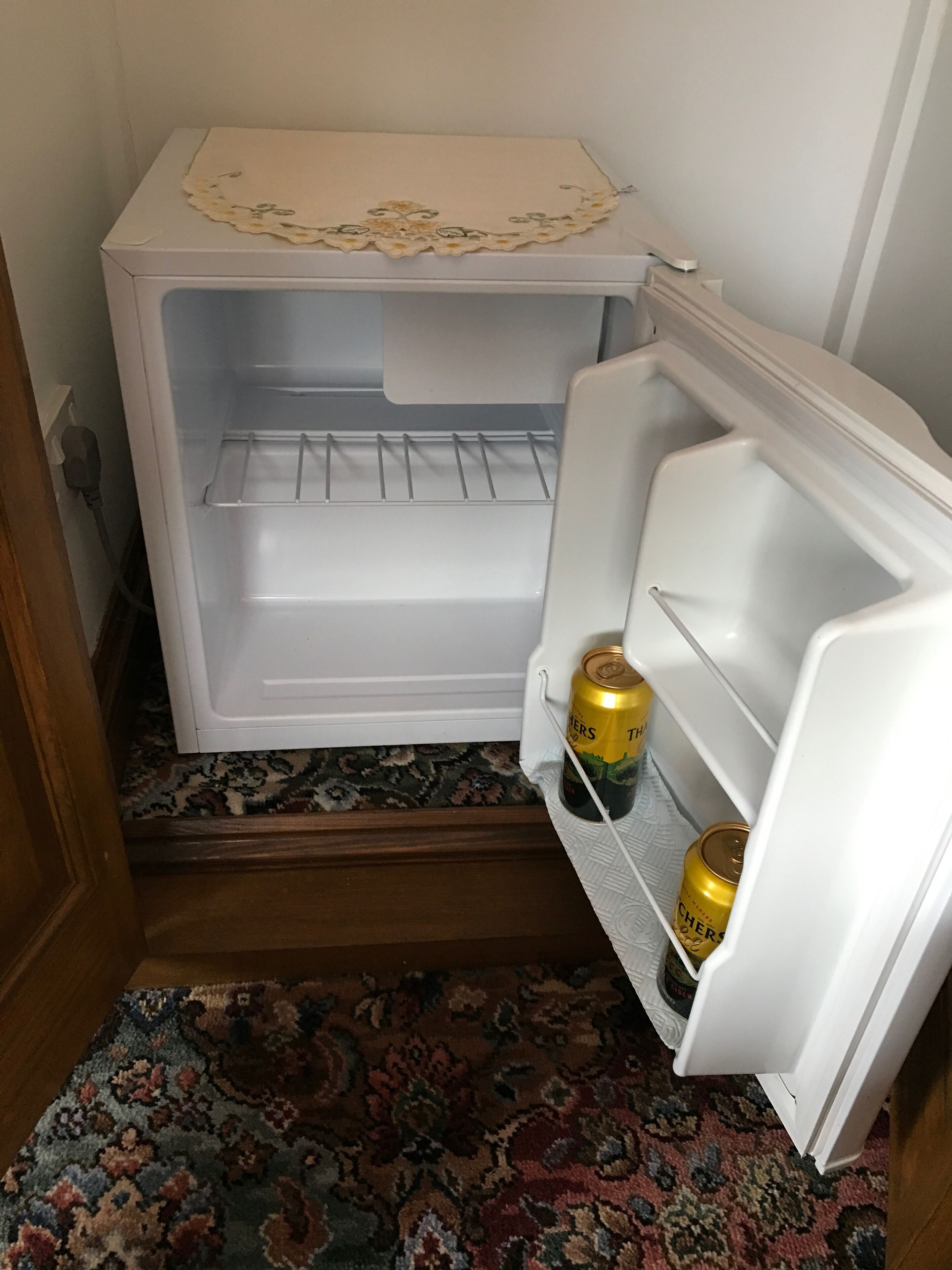 A small white refrigerator with a floral-patterned top. It has two empty shelves and a freezer compartment.