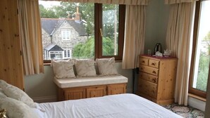 Une chambre à coucher avec un grand lit, une commode en bois et un banc agrémenté de coussins.