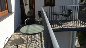 Un balcon avec une table et des chaises en verre, une porte et une fenêtre.