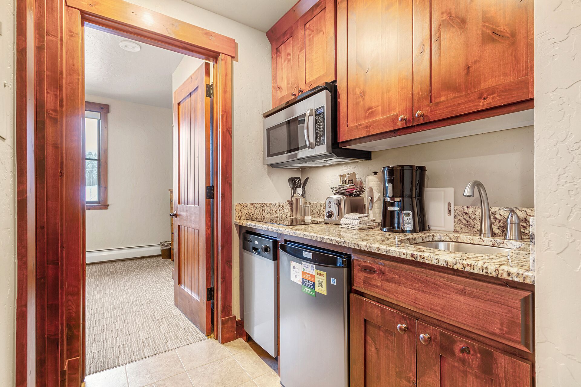 A kitchen with wooden cabinets, a microwave, a toaster, a coffee maker, and a dishwasher.
