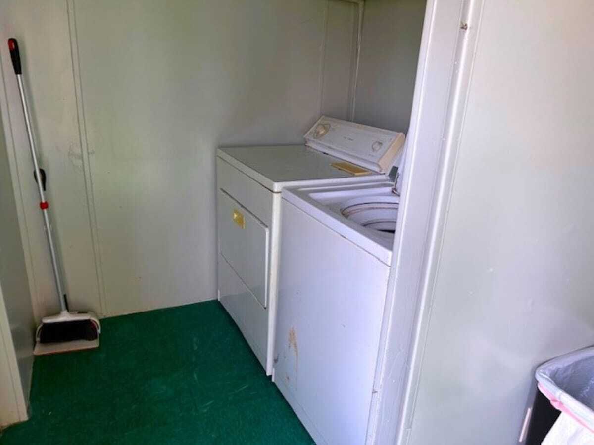Une buanderie équipée d’un lave-linge, d’un sèche-linge et d’une serpillière appuyée contre le mur.