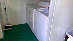 A laundry room with a washing machine, a dryer, and a mop leaning against the wall.