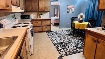Une cuisine compacte avec des meubles en bois, une cuisinière et un coin repas comprenant une table et des chaises.