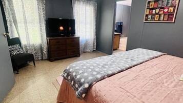 A bedroom with a bed, a dresser, a television, and a wall with framed pictures.