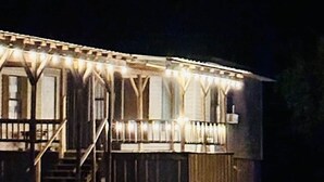 A building with a porch, stairs, and a fenced area.