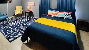 A bedroom with a bed, a chair, a desk, and a ceiling fan.
