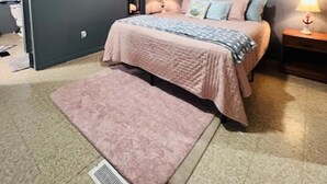 A bedroom with a bed, bedside tables, a rug, and wall art.