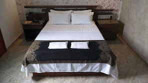 A hotel room with a large bed, two bedside tables, a nightstand, and a wall-mounted electrical outlet. - Hotel Millennium (São Paulo)