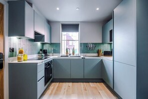 Een moderne keuken met grijze kasten, een centraal eiland en een raam voor natuurlijk licht.