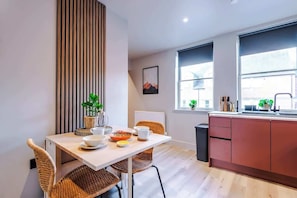Een moderne keuken met een eethoek, met een wand van houten latten, een groot raam en uitzicht op buiten.