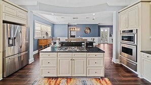 Una cocina amplia con una isla central, electrodomésticos de acero inoxidable y un ventanal que proporciona luz natural.