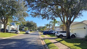 Una calle residencial flanqueada por casas, coches aparcados y árboles.