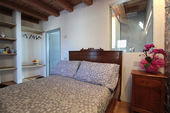 A bedroom with a bed, wooden headboard, and a nightstand with a vase of flowers.