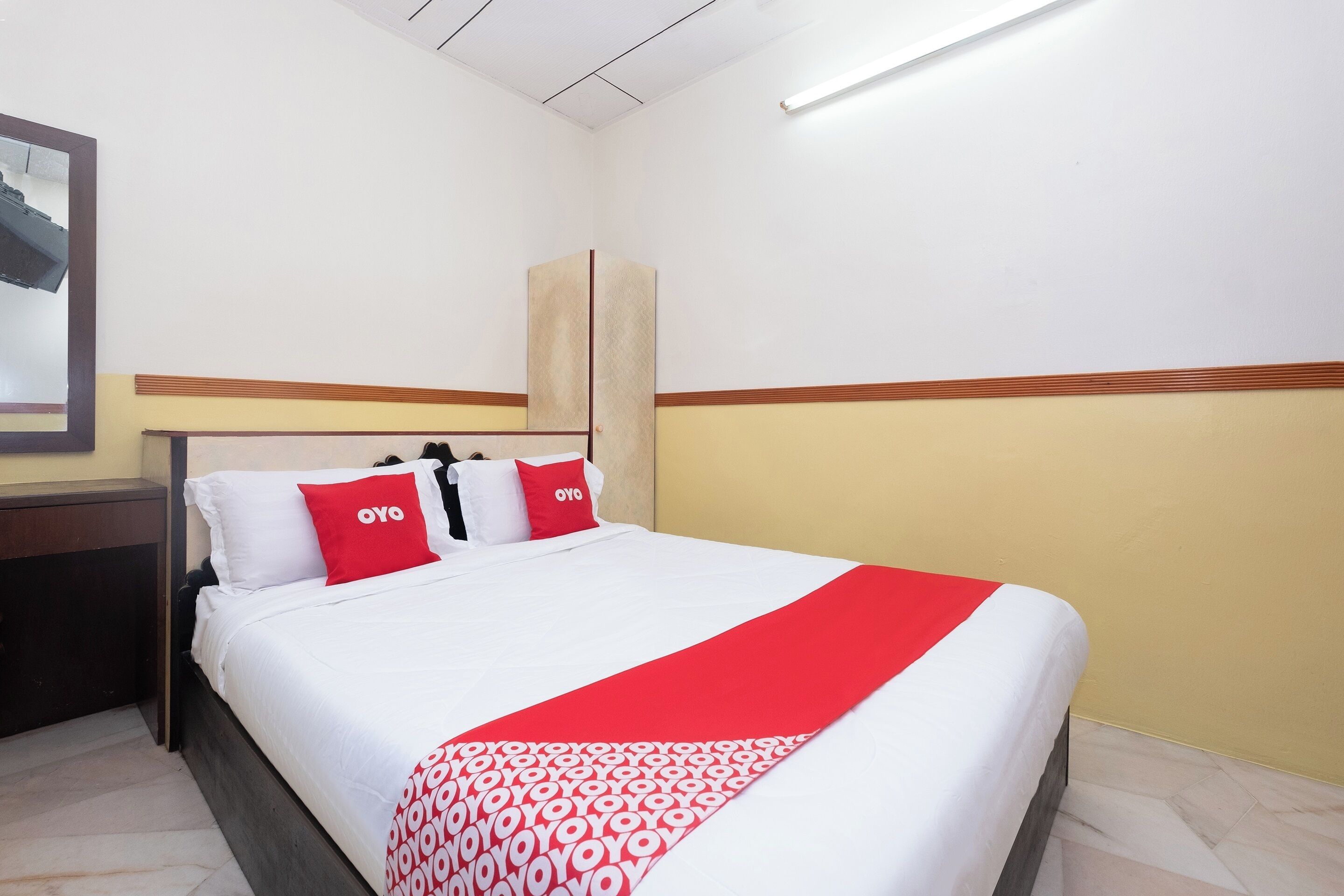 Een hotelkamer met een bed, nachtkastje, spiegel en kledingkast.