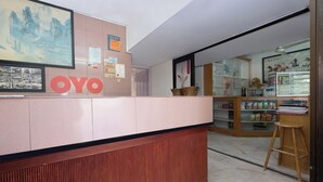 Ένας χώρος υποδοχής με μια μεγάλη επιγραφή «OYO», έναν πίνακα με τοπίο σε κορνίζα και έναν πίνακα ανακοινώσεων με διάφορες σημειώσεις.