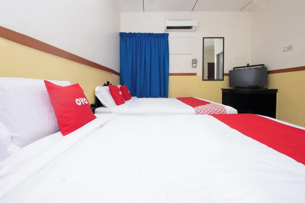 A hotel room with two beds, a television on a stand, and a blue curtain.