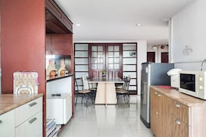 Una cucina moderna con zona pranzo, caratterizzata da un'isola centrale, mobili in legno e un forno a microonde.