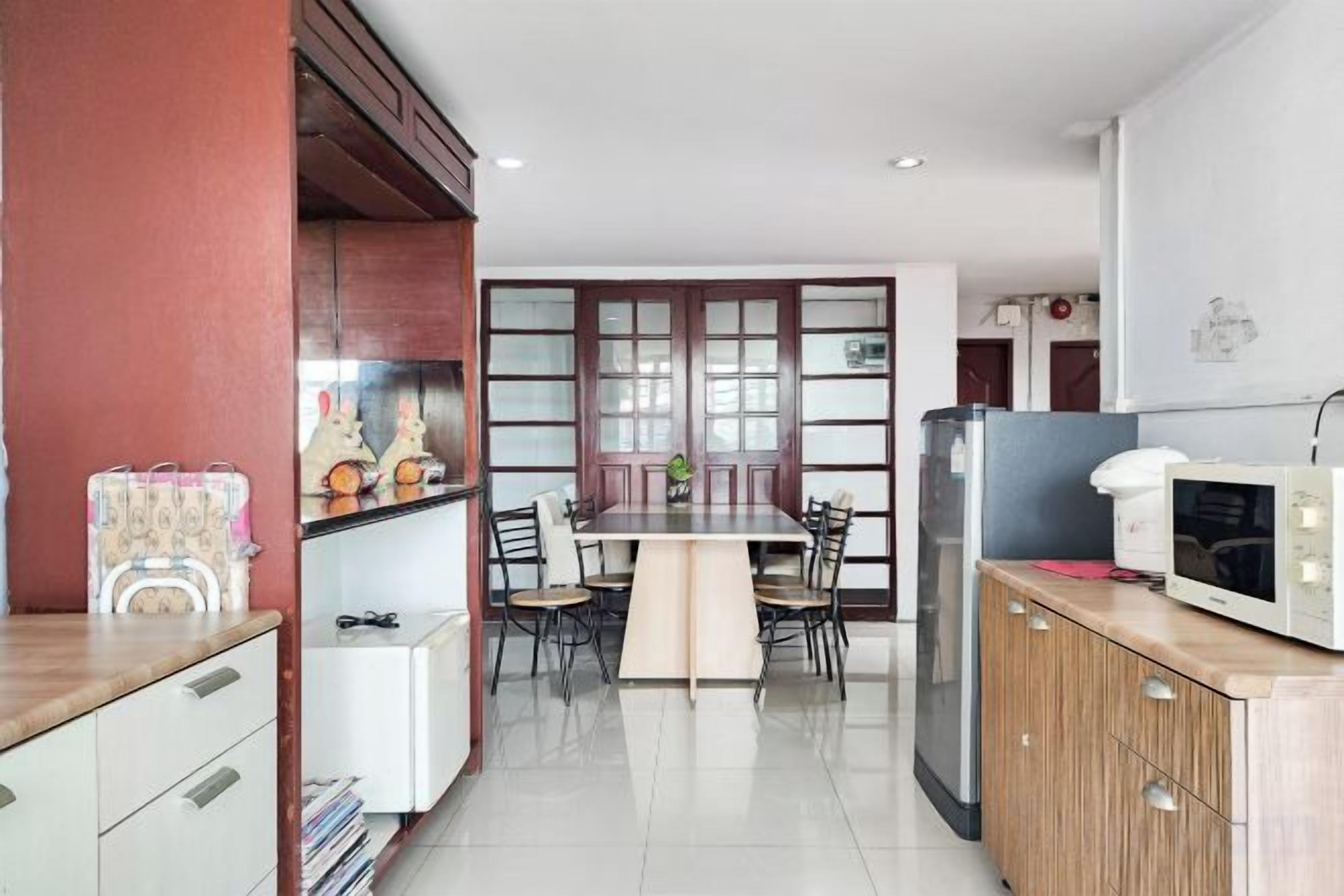 A compact kitchen with a dining area, white cabinets, a microwave, and a refrigerator.