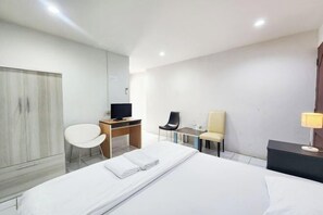 A hotel room with a bed, a desk with a computer, a chair, a TV, and a lamp. - Freesia Bangphi Guest House (Bang Phli)