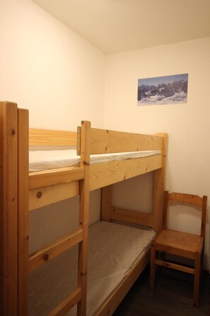 A bunk bed room with a wooden chair and a framed picture on the wall.