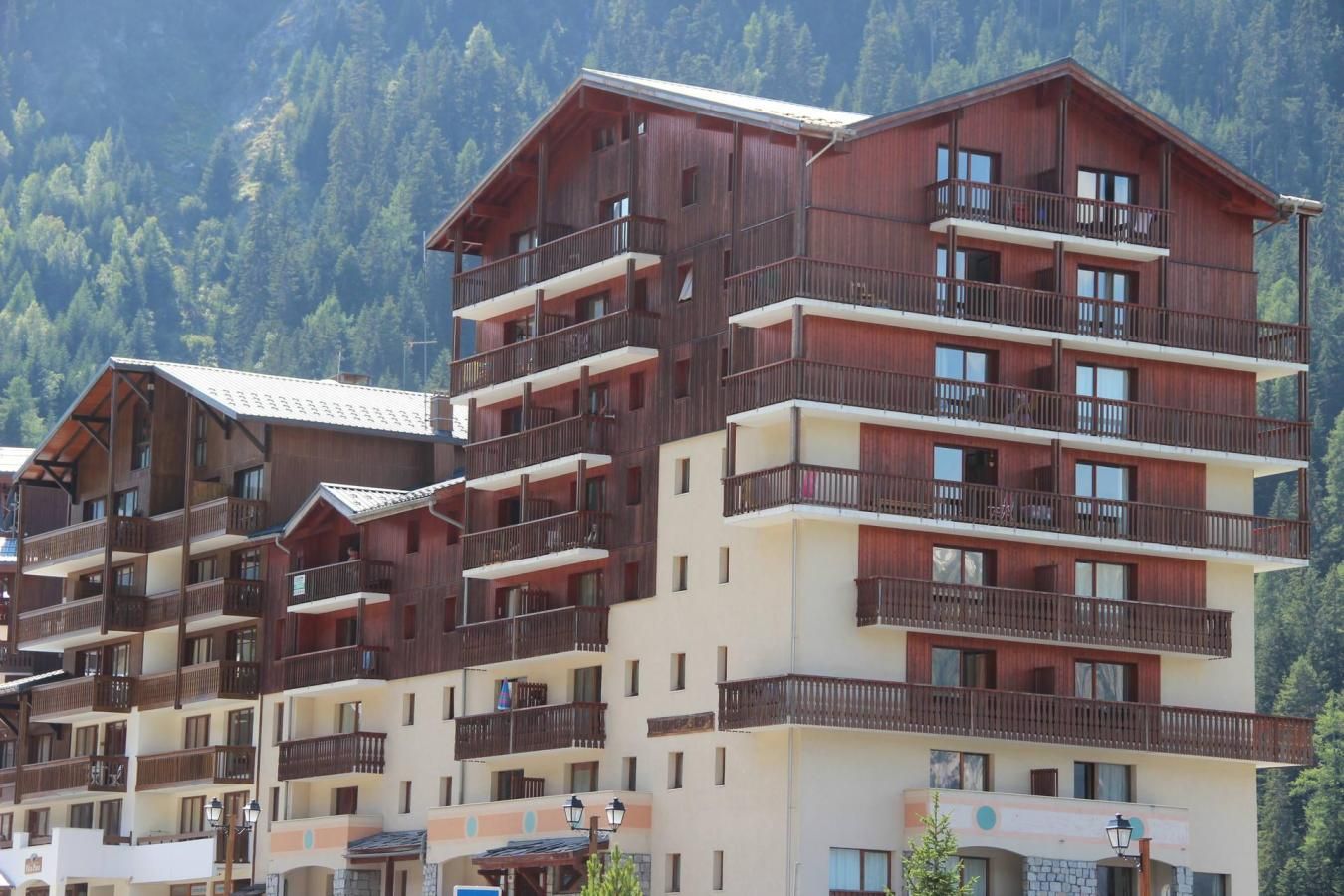 Un hôtel à plusieurs étages, doté de balcons et situé dans un cadre montagneux.