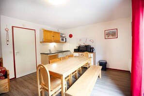 Een kleine keuken met houten kastjes, een magnetron en een spoelbak.
