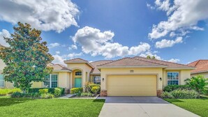 A single-story house with a garage, a well-maintained lawn, and a large tree in the front yard.