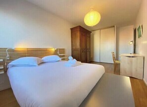 Relax in a spacious room with a large bed, a wardrobe, a desk, and a chair.