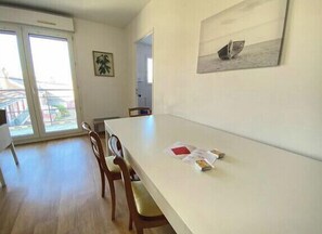 Enjoy meals in this dining area with a long table and four chairs, surrounded by natural light and a beautiful piece of artwork.