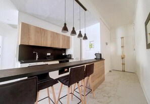 Enjoy cooking in this well-equipped kitchen with a sleek countertop, wooden cabinets, and pendant lights.