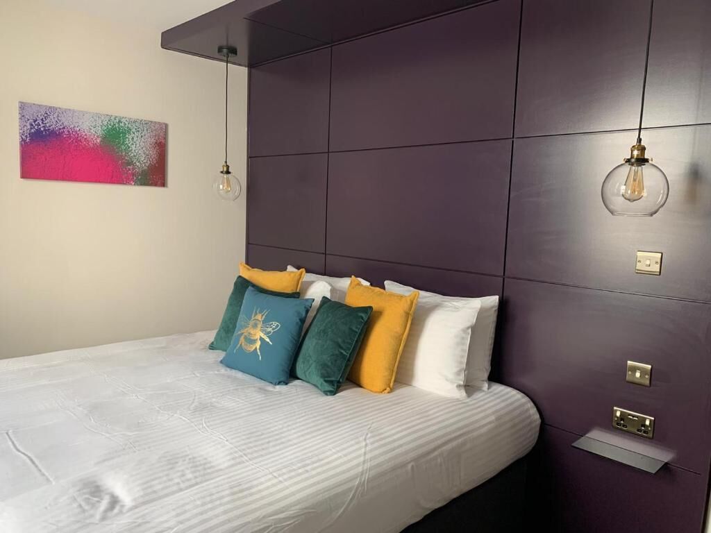 A neatly made bed with a white sheet and multiple colorful pillows.
