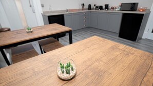 Een moderne keuken met grijze kastjes, een houten eettafel en een cactus in een glazen schaal.