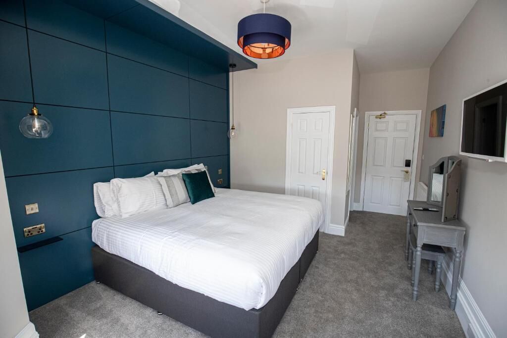 Ein Schlafzimmer mit einem großen Bett, einem Schminktisch, einem Spiegel und einer Tür.