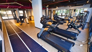A gym with treadmills, weight machines, and a wooden floor. - STAY Urbà Home (Goiania)