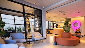 A modern lobby with seating areas, a bar, and a large window. - STAY Urbà Home (Goiania)