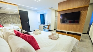 A hotel room with a large bed, a desk, a chair, a TV, and a wardrobe. - STAY Urbà Home (Goiania)