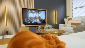 Una sala de estar moderna con una televisión, una mesa de centro redonda y un sofá.