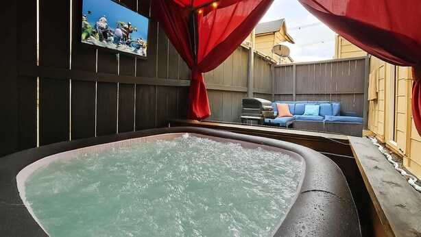 Un jacuzzi con terraza de madera y un sofá azul al fondo.
