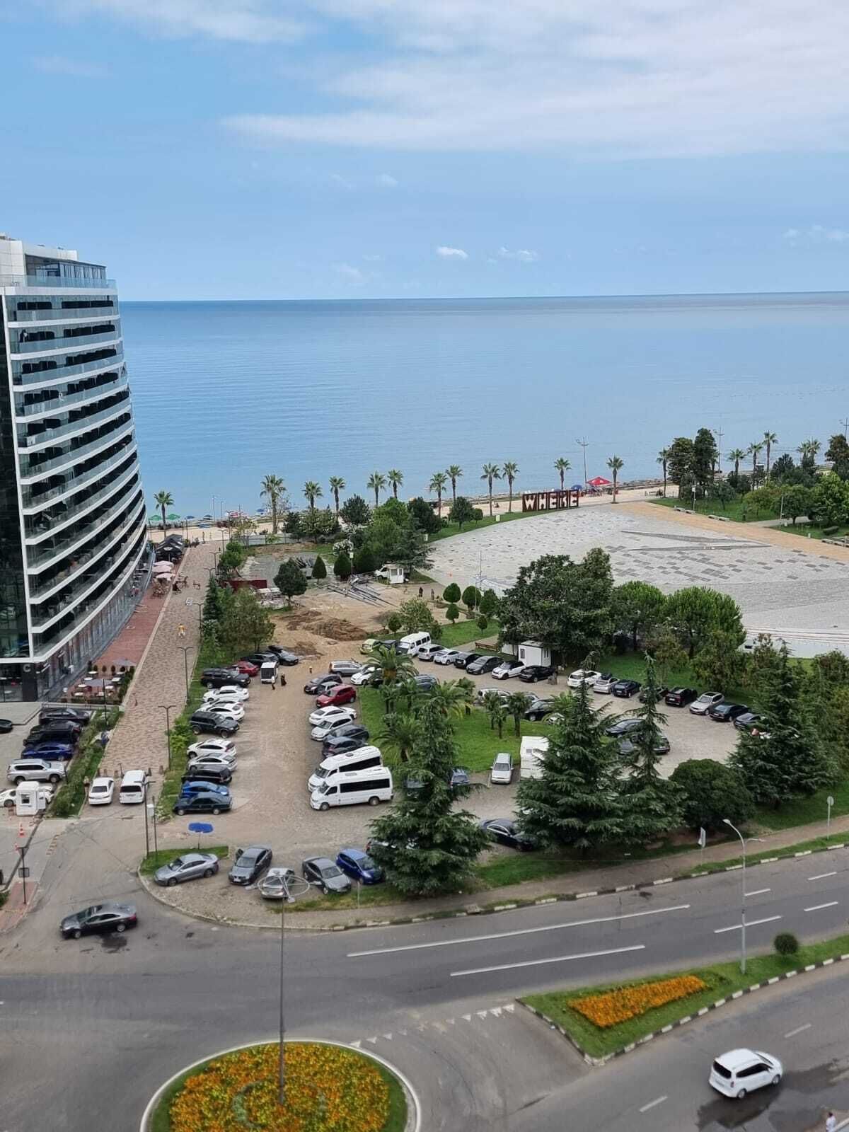 A coastal hotel with a parking lot, a beach area, and a view of the sea.