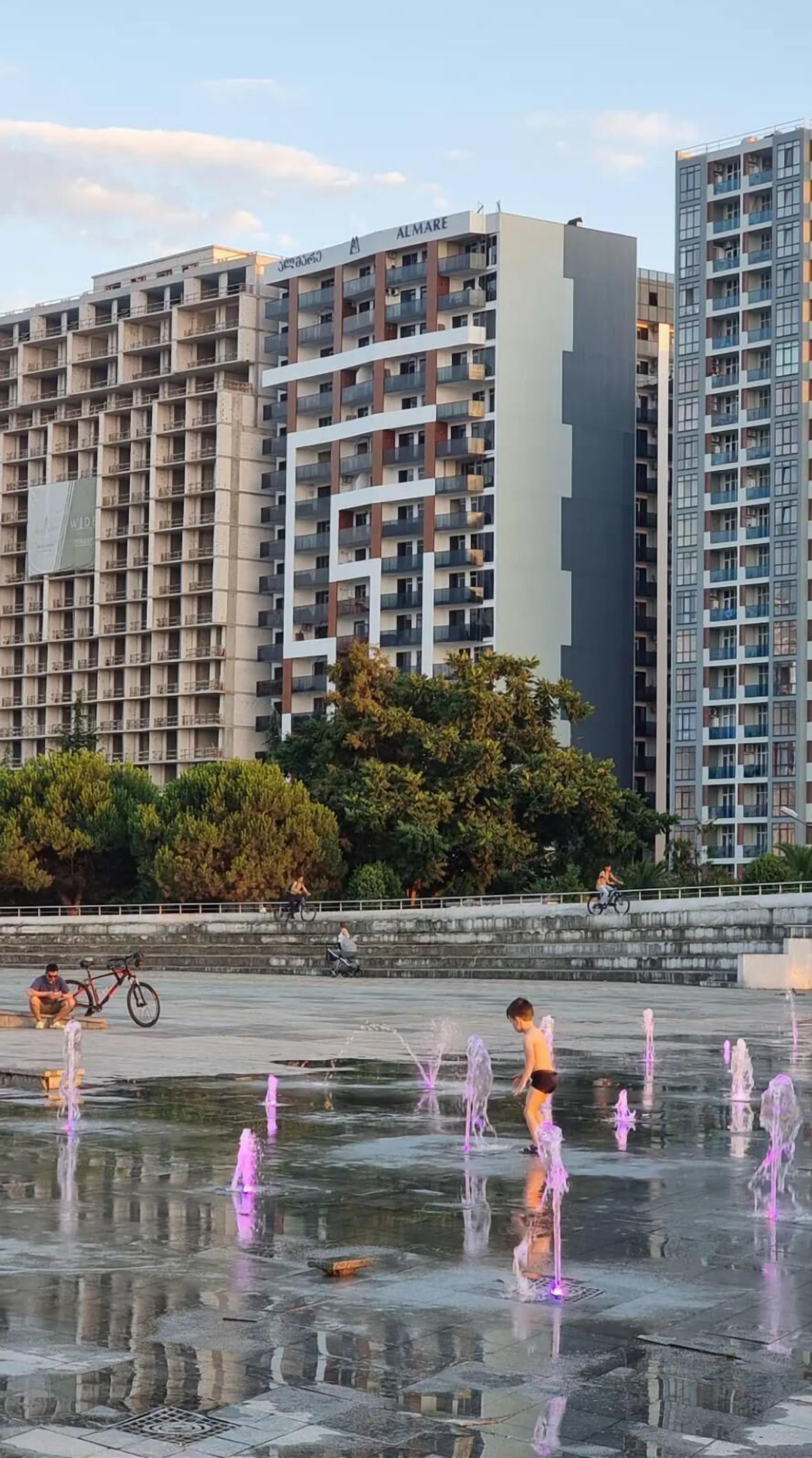 A modern building with multiple balconies and a water feature in the foreground.