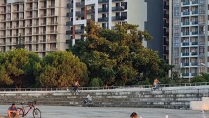 A modern building with multiple balconies and a water feature in the foreground. - Tal's Apartment  (Batumi)