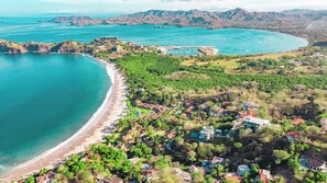 Eine Luftaufnahme einer Küstenregion mit Strand, Wohnhäusern und einem großen Gewässer.