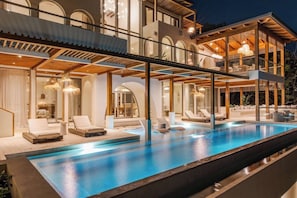 Un immeuble moderne à plusieurs étages, doté d’une piscine et d’un espace extérieur aménagé pour se détendre.