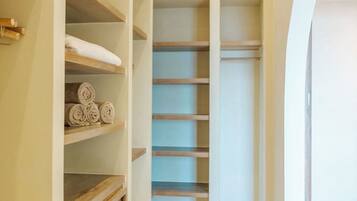 Un vestidor amplio con estantes y cajones, suelo de baldosas y una luz en el techo.