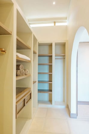 Un vestidor amplio con estantes y cajones, suelo de baldosas y una luz en el techo.