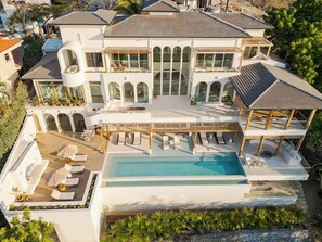 Une grande maison moderne dotée d’une piscine, de nombreux balcons et d’un patio couvert.