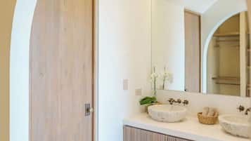 Un bagno moderno con una porta in legno, un ampio specchio e due lavabi in pietra.