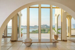 Amplia habitación con un amplio ventanal de arco que da a una masa de agua y un paisaje distante.