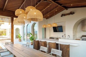 Una cocina moderna con una isla grande, luces colgantes y un televisor de pantalla plana.