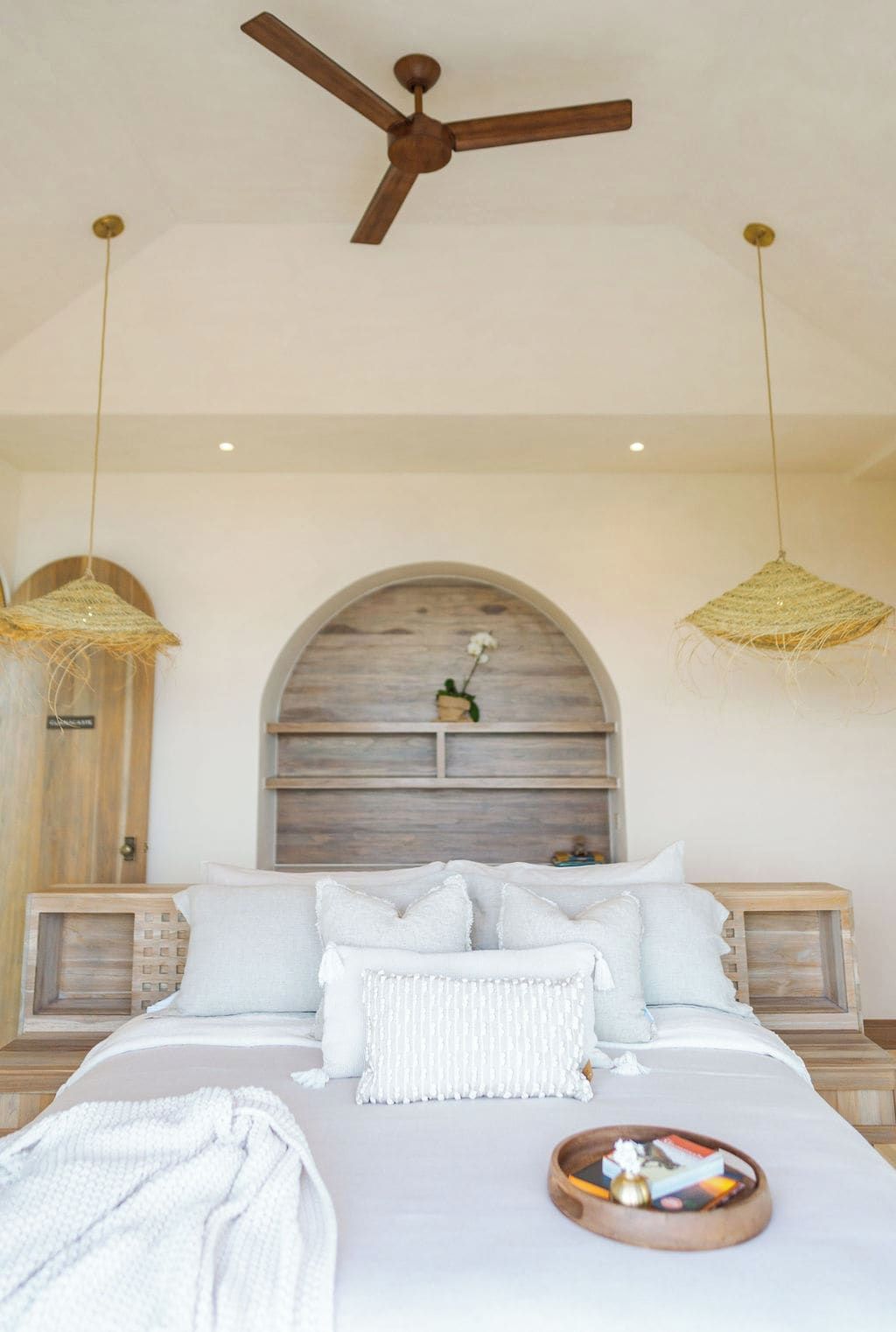 Una camera da letto con un letto, due comodini, una ventola a soffitto e due lampade a sospensione.